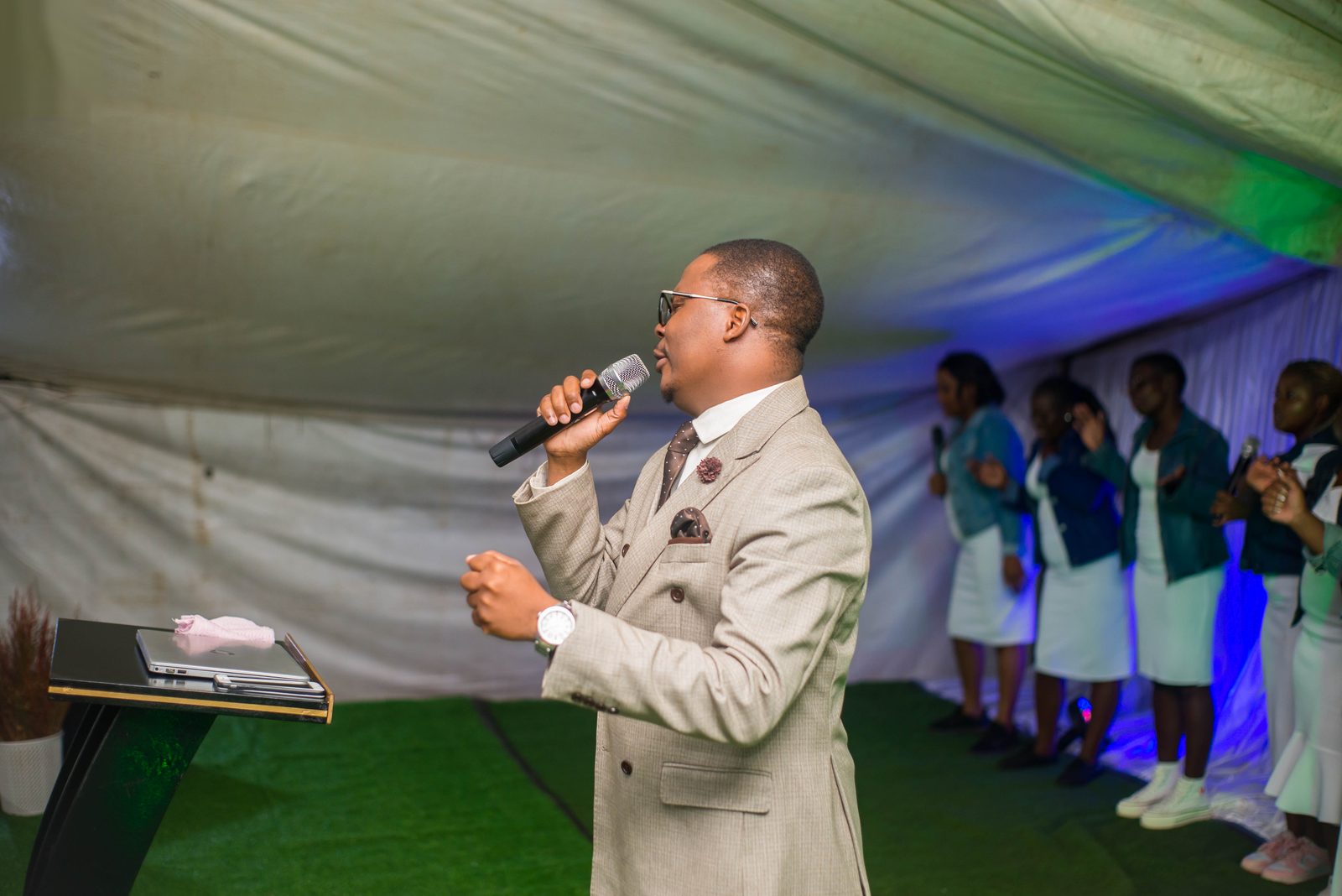 Apostle preaching under the tent, hands lifted