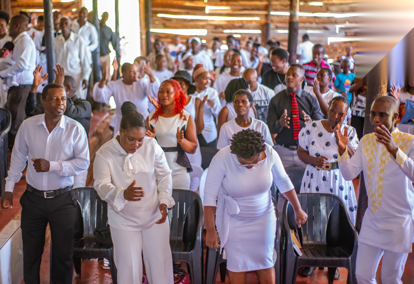 White-clad congregation worshipping with raised hands
